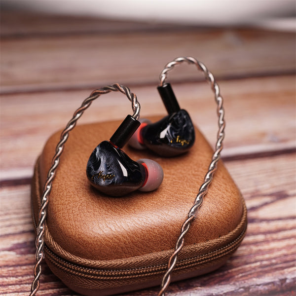 Gray QOA Vesper earphone on a leather case